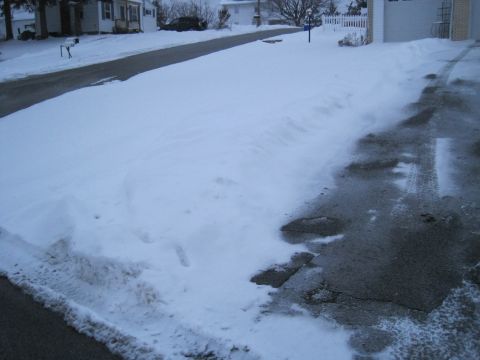 2004 Aston Martin Virage - A dark SUV is parked on a snow-covered street, with tire tracks visible on the partially cleared asphalt.