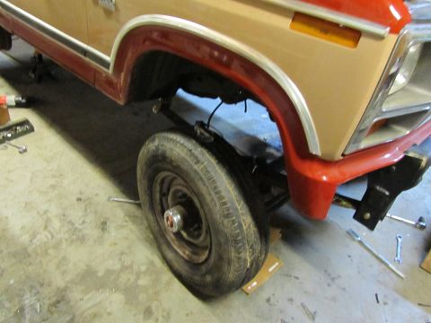 1984 Ford Bronco - A tan and red Ford Bronco is shown from the front quarter angle with its front wheel raised.