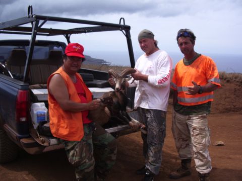 1991 Ford Bronco - Hunters pose with their ram kill beside a pickup truck, with a coastal view in the background.