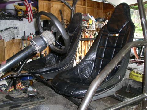 1979 Ford Bronco - Vehicle interior shows racing seats and a steering wheel, with a roll cage structure.