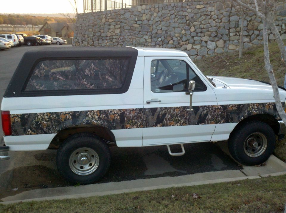 Side view of a white 1995 Ford Bronco with camouflage body stripe