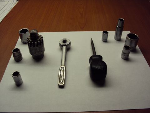 1965 Ford Mustang - A collection of various sockets, a ratchet, and a screwdriver are displayed on a white surface.