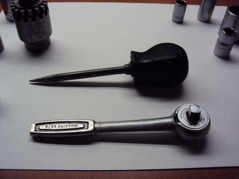 1965 Ford Mustang - A collection of tools, including a ratchet and an awl, are laid out on a flat surface.