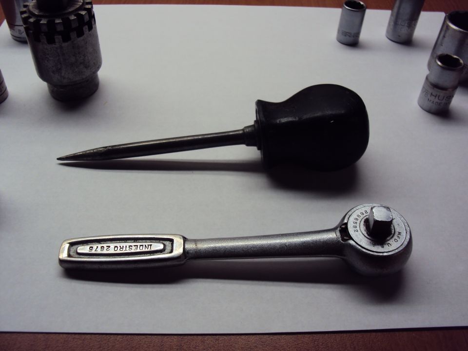 Ratchet and awl tools on a white surface with socket wrenches