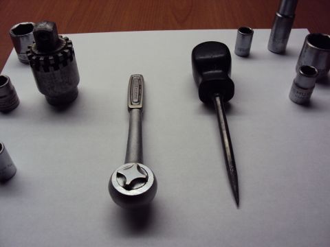1965 Ford Mustang - A collection of tools including a socket wrench set and a screwdriver are laid out on a white surface.