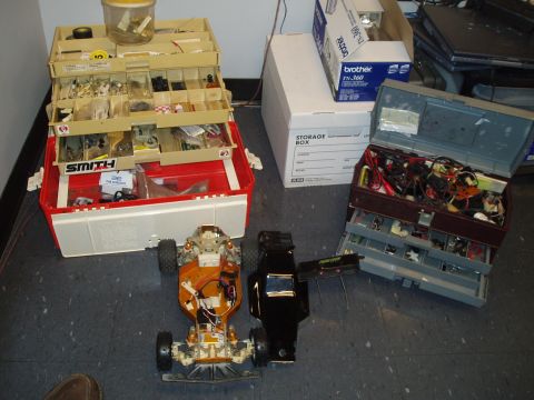 1996 Ford Bronco - Two RC car chassis and bodies are laid out next to several opened toolboxes containing various parts and wires.