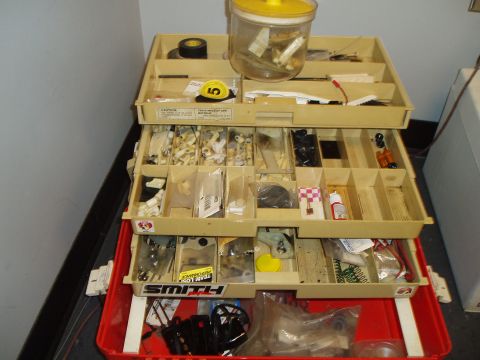 1996 Ford Bronco - A tan tool chest is filled with various small parts and supplies, organized into compartments.