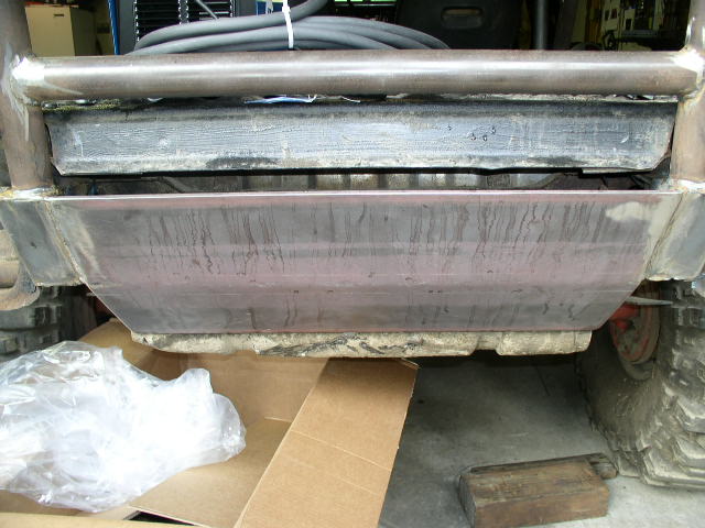 Bare-steel tube rear bumper and fabricated panel on a stripped 4x4 in a shop