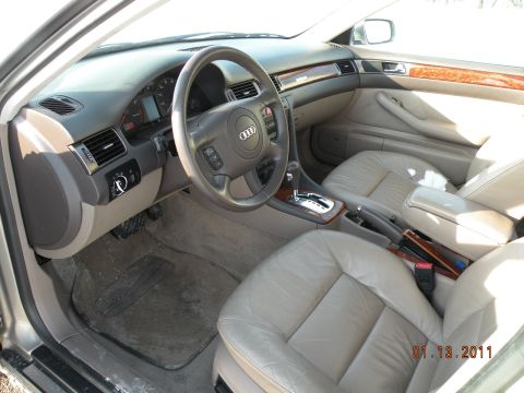 2000 Audi A6 - The interior of a car is shown, leather seats and wood trim accents on the dashboard and doors.