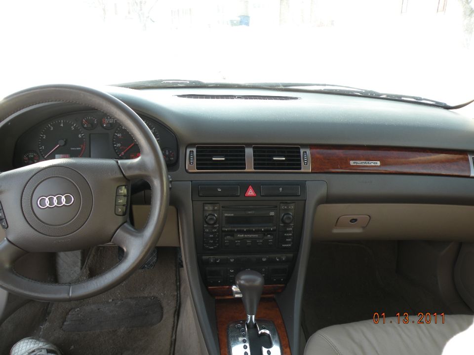 Audi sedan dashboard with four-ring steering wheel, wood quattro trim and factory CD stereo