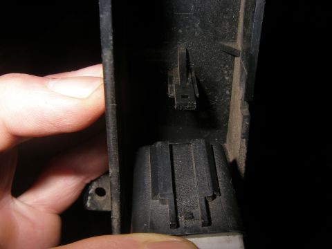 1990 Ford Bronco - A hand holds a section of black plastic, revealing a clip and a ribbed socket.