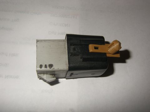 1990 Ford Bronco - A close-up view of an automotive relay connector, showing its plastic components and visible markings.