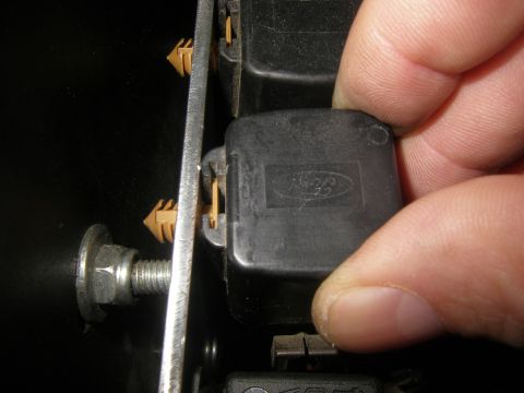 1990 Ford Bronco - A hand is shown removing a black Ford relay from a panel.