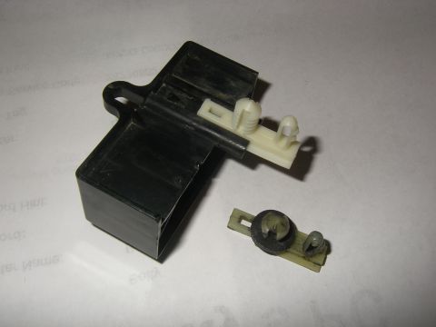 1990 Ford Bronco - This image shows a black plastic relay housing with white plastic clips and a separate clip assembly, likely a component from a vehicle's e…