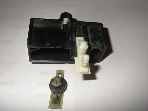 1990 Ford Bronco - Close-up of a disassembled automotive relay housing and its associated clip.