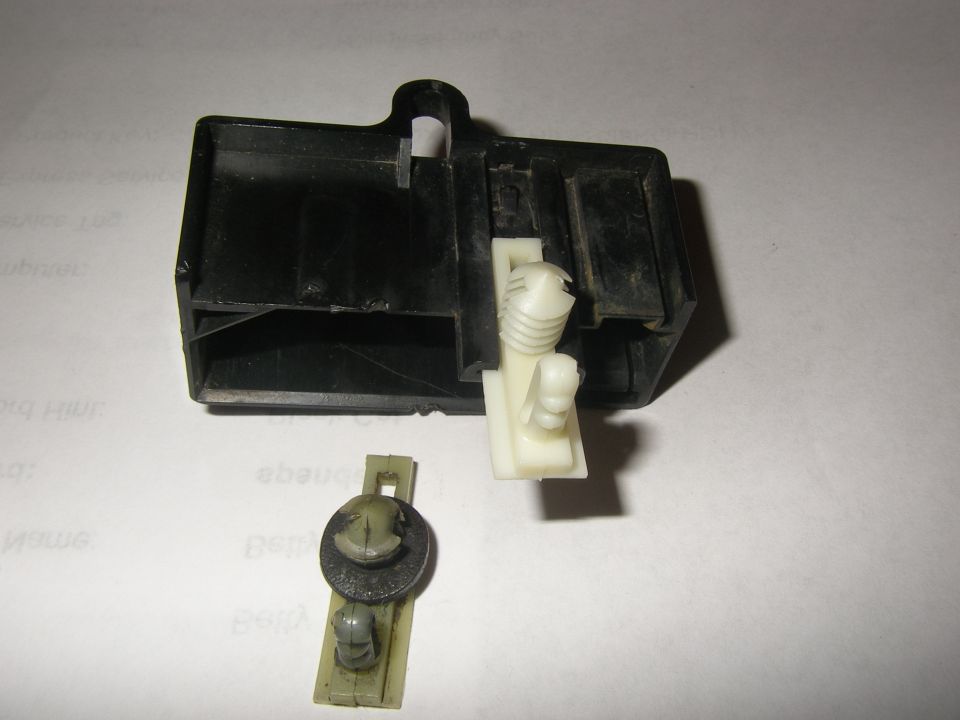 Black plastic automotive relay housing with a separate plastic clip and fastener