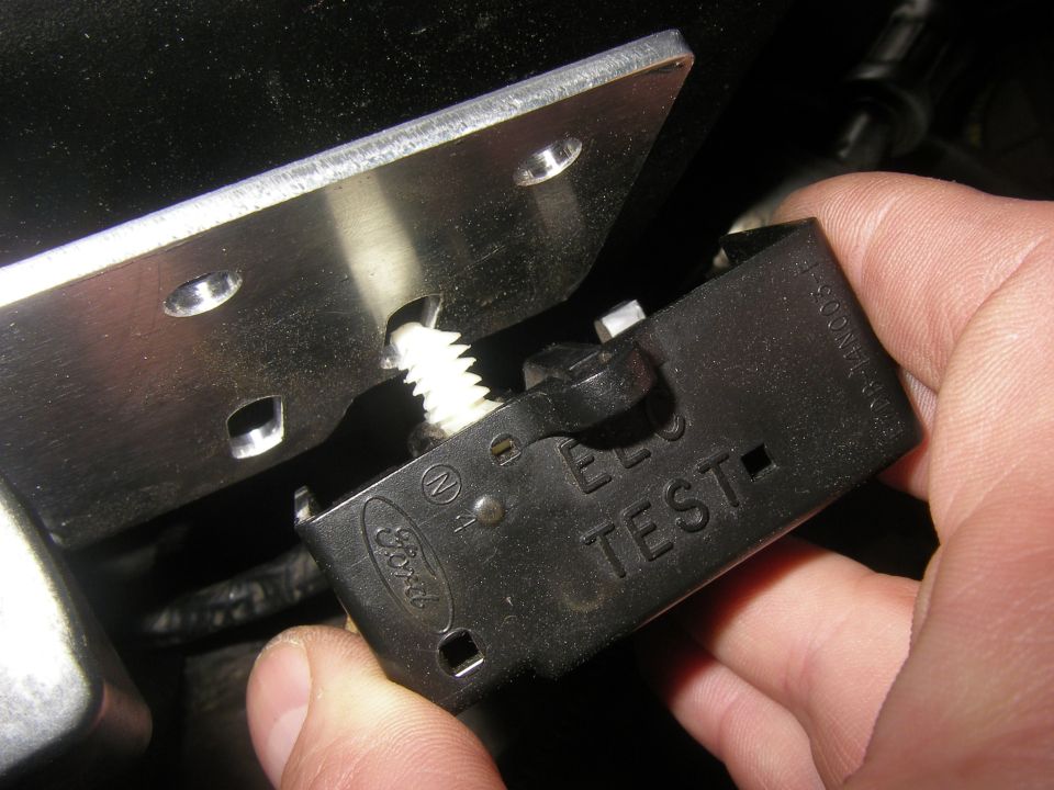 Ford logo on black plastic relay with 'TEST' text, held by a hand