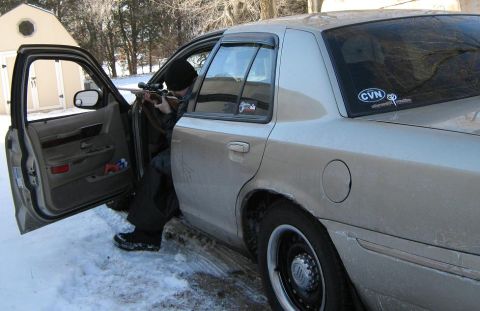 2000 Mercury Grand Marquis - A person aims a rifle from inside a car parked in the snow.