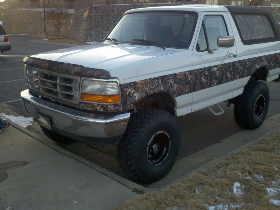 White Ford Bronco with camouflage body graphics and lifted suspension