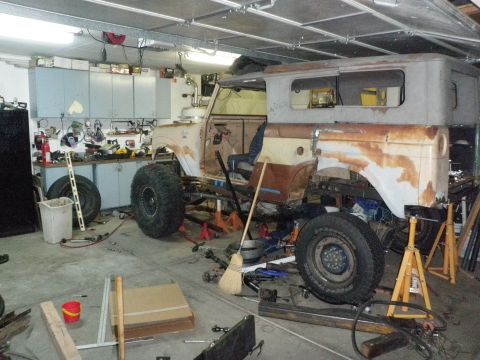 1961 International Scout 800 - A 1961 International Scout 800 body is undergoing modifications in a cluttered garage.