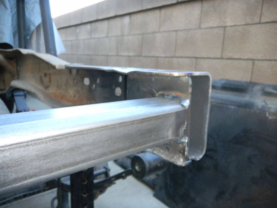 Welded metal frame section with visible welds and holes, on a jack stand