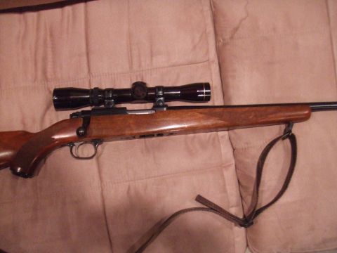 1996 Ford Bronco - Bolt-action rifle with scope, resting on a quilted background.