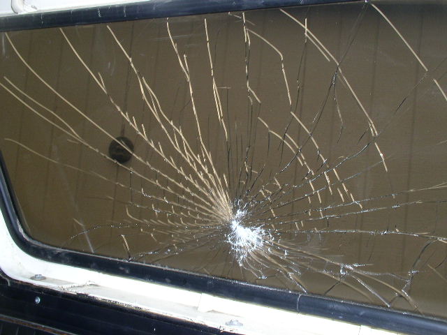 Cracked windshield with starburst impact point and spider-web cracks
