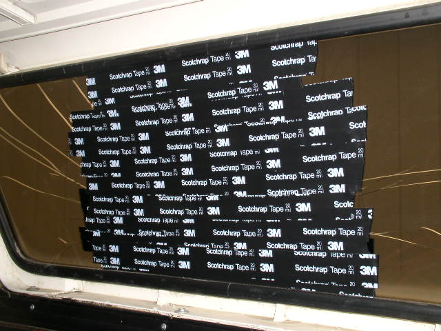 Cracked vehicle window patched with black 3M Scotchrap tape strips