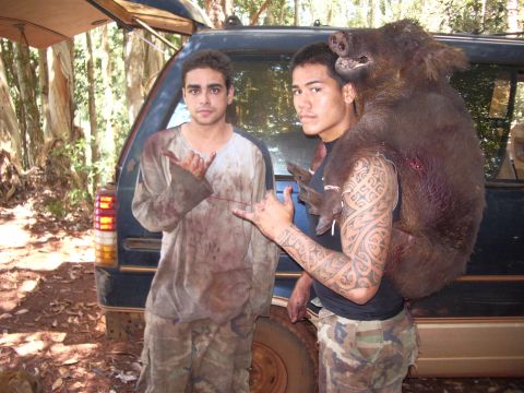 1991 Ford Bronco - Two men pose with a wild boar after a hunt, with a dark SUV in the background.