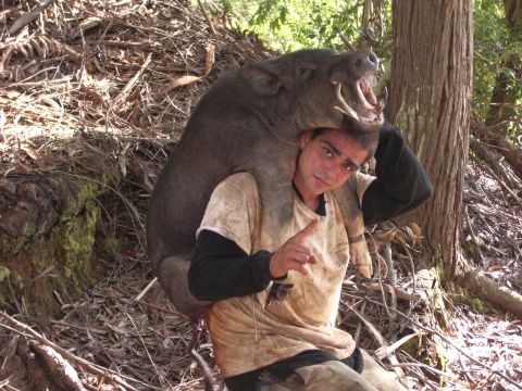 1991 Ford Bronco - A man poses with a wild boar draped over his shoulders in a wooded area.