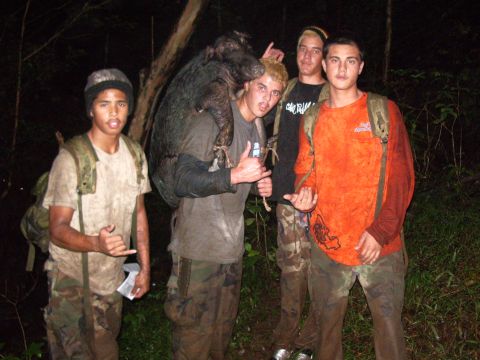 1991 Ford Bronco - A group of hunters proudly display their successful wild boar hunt in a wooded area at night.