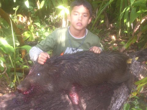 1991 Ford Bronco - A young hunter proudly displays a wild pig after a successful hunt in a wooded area.