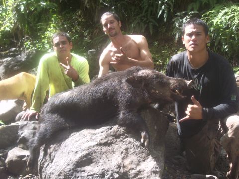 1991 Ford Bronco - Hunters pose with their wild boar catch in a natural setting, with a dog visible in the background.