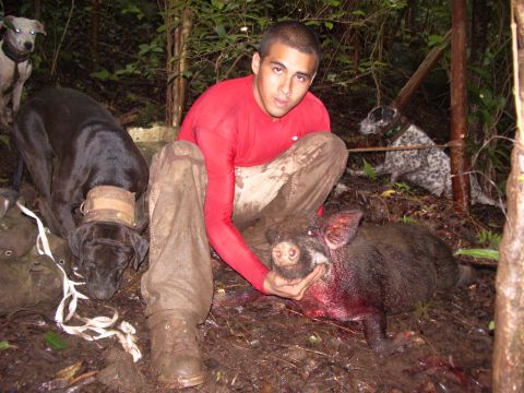1991 Ford Bronco - Hunter with his dogs and a harvested hog in a muddy, wooded environment.