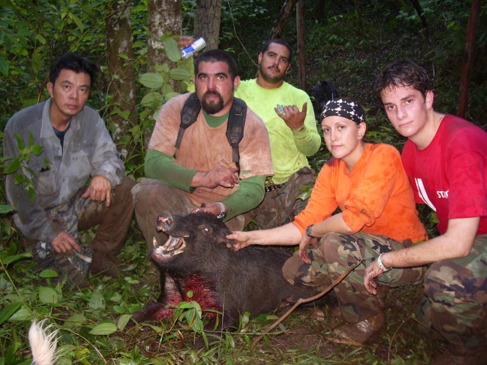 Group of five people posing with a dead wild boar in a forest