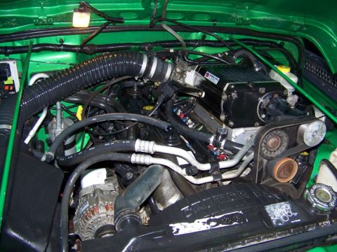 2004 Jeep TJ - Engine bay view showing a black supercharger unit installed on the engine.