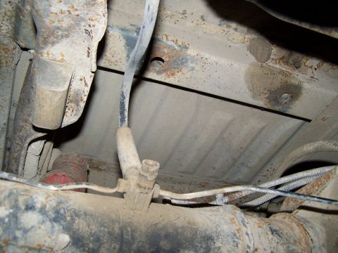 1989 Ford Bronco - Close-up of the undercarriage, revealing suspension components and fuel lines, with SuperMotors.net watermark.