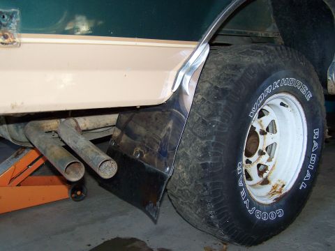 1989 Ford Bronco - Rear view of a vehicle showing a tire, exhaust, and lower body panel. The tire is a Goodyear Workhorse Radial.