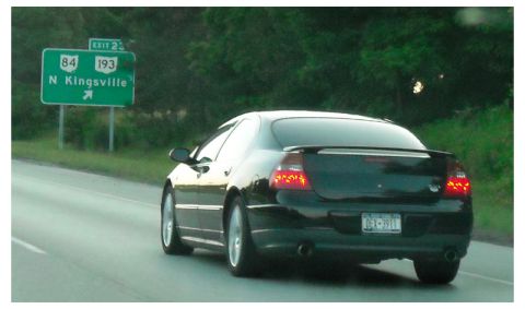 2002 Chrysler 300M - Rear view of a black 2002 Chrysler 300M sedan on the highway, with a green exit sign in the background.