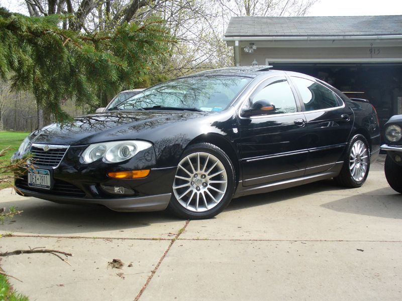 Black 2002 Chrysler 300M sedan parked in a driveway, front 3/4 view, with a garage in the background