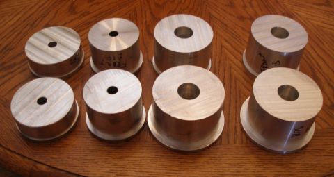 2010 Hyundai Genesis - Several aluminum suspension spacers are laid out on a wooden surface, some labeled for front and rear installation.