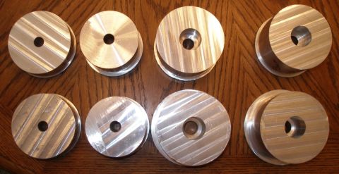 2010 Hyundai Genesis - Eight aluminum suspension spacers are laid out on a wooden surface. The parts appear to be for vehicle suspension modification.
