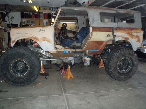 1961 International Scout 800 - A 1961 International Scout 800 is shown in a garage, undergoing modifications with oversized tires and a lifted chassis.