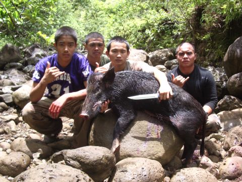 1991 Ford Bronco - Hunters pose with their wild boar kill in a rocky, wooded area.