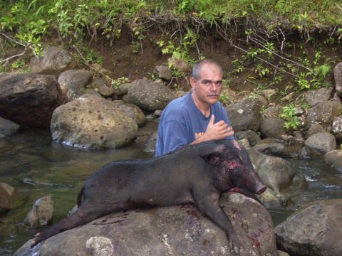 1991 Ford Bronco - A man poses with a large wild boar he has apparently hunted, resting on rocks near a stream.