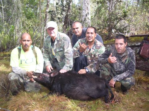 1991 Ford Bronco - Hunters pose with a wild hog they have bagged in a wooded area.