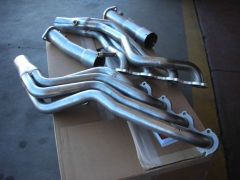 2004 Ford Crown Victoria - A set of shiny metal exhaust headers are laid out on a cardboard box.