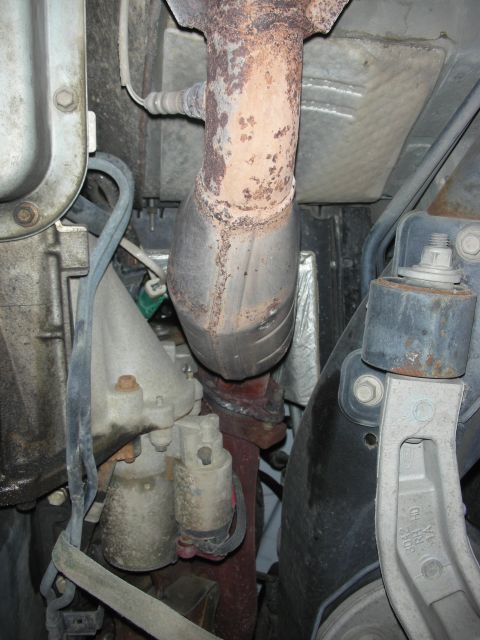 2004 Ford Crown Victoria - Underside view of exhaust system components, including the catalytic converter and associated piping.