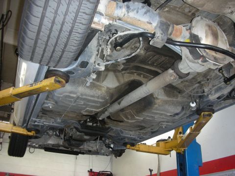 2004 Ford Crown Victoria - Car's undercarriage is visible as it's raised on a service lift for maintenance.