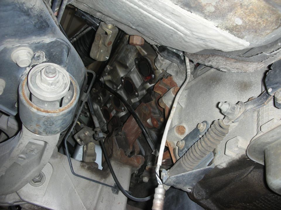 underneath view of a vehicle's engine, exhaust manifold, and transmission components